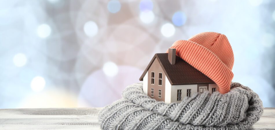 Figure,of,house,and,warm,clothes,on,table,against,blurred